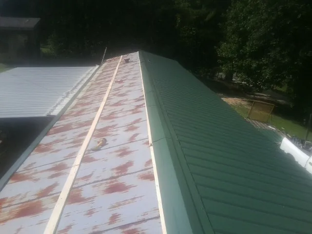 Old rusted panels beside newly installed green metal roofing — Wind Damage Roof Repair by Roofing Brothers in Pawleys Island