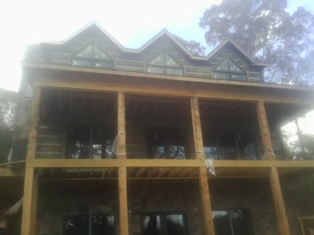Dormers and porch framing on a large log home under construction — Roof Coating work by our crew in Pawleys Island