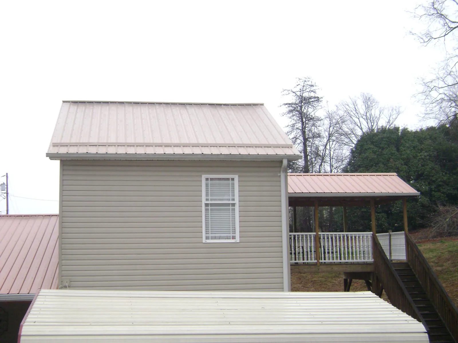 Tan metal roofs on a two story addition and attached porch, from a Roof Replacement job in Pawleys Island