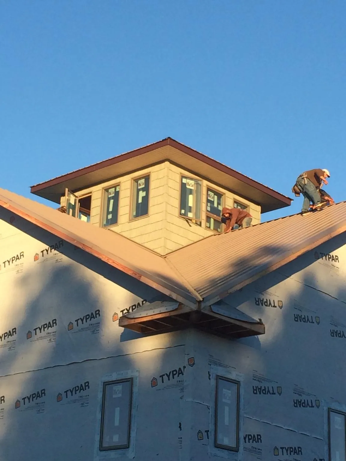Roofers working around a rooftop cupola on a new metal roof at sunset — Roof Waterproofing in Pawleys Island by Roofing Brothers